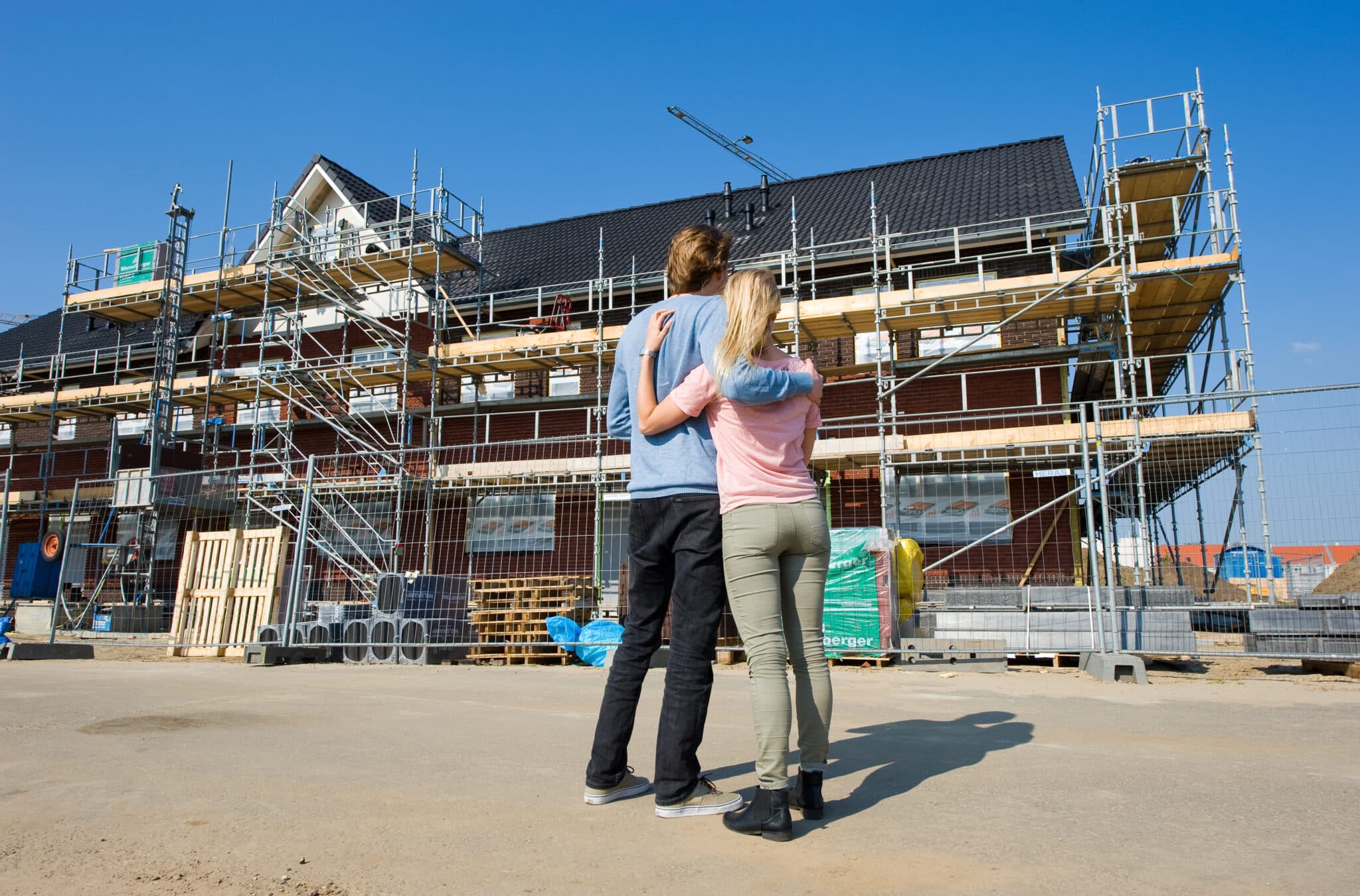 Een jong stel bekijkt de vorderingen van hun nieuwbouwwoning